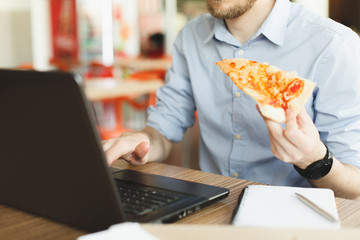Person holding a Pizza and working on Laptop