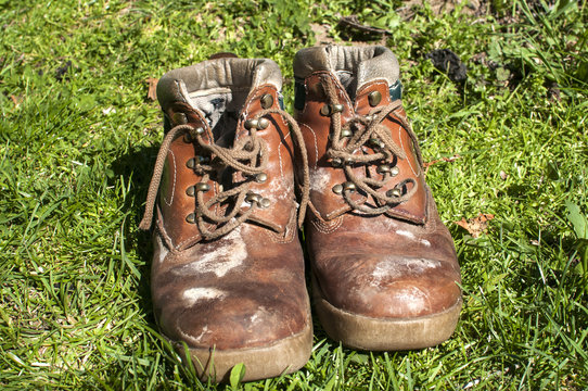 Old used weathered moldy grunge man's leather shoes on green grass field