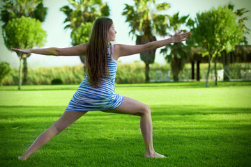 Fototapeta na wymiar Young woman exercising on green grass