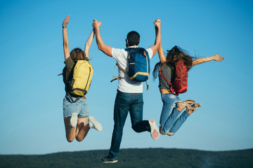 Three friends jumping on mountain top on blue sky