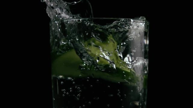 In a glass with soda fall two slices of cucumber. Slow mo