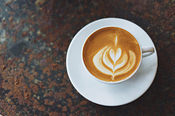 A cup of coffee on rustic background with beautiful latte art.