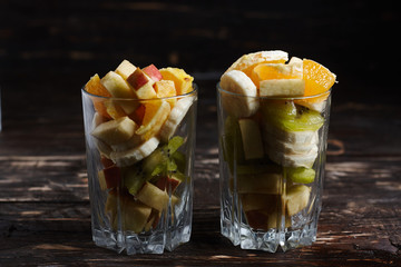 Fruit desserts made at home. 2 cups with sliced fruit. Fresh fruits on a wooden background.
