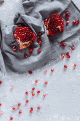 chunks of ripe red pomegranate, fork and knife on a grey kitchen towel on a grey white background with candles, seeds top view food photos