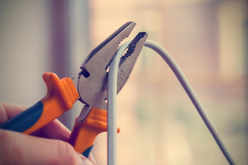 Worker man cutting electric wires with pliers