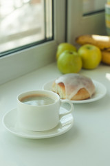 Cup of coffee, fruits and roll on a white background, window, Blogger lifestyle, Coffee house. Sunlight rays.
