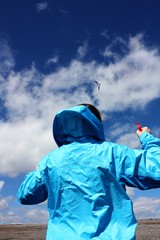 Girl flying a kite on the beach against a beautiful blue sky.