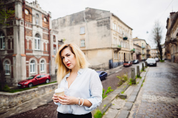 The stylish girl keeps a cup of coffe