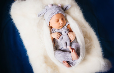 Fototapeta premium Child in knitted suit dreams on white pillow