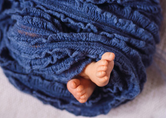 Feet of newborn baby enveloped in blue scarf