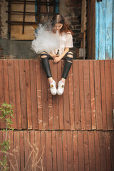 Beautiful vape teenager. Portrait of a pretty young white girl with red curly hair vaping an...