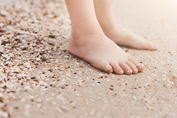 Fototapeta na wymiar Barefoot child legs on sand