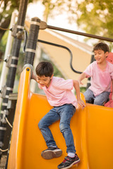 Fototapeta na wymiar Little boys playing slider at playground