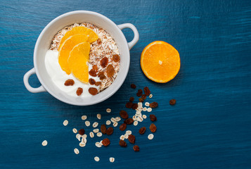 Muesli with yogurt and oranges on a dark background. Concept of dietary nutrition, top view.