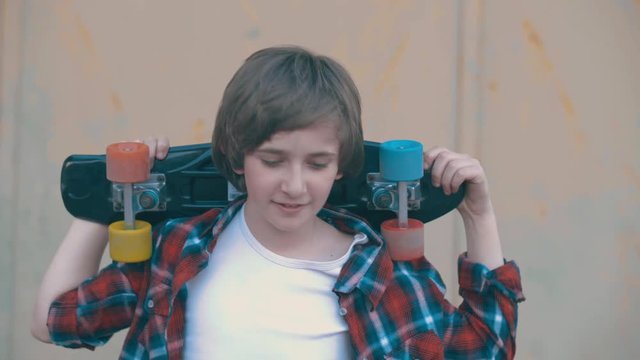 boy holding a skateboard and looking at the camera. shot in slow motion