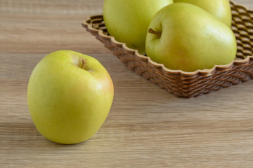 Yellow apples in a basket on the table.