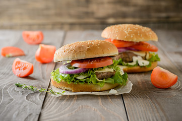 Home made hamburger with beef, onion, tomato, lettuce and cheese. Fresh burger closeup on wooden rustic table