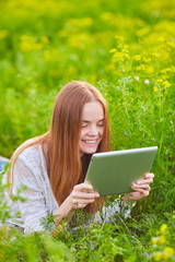 Smiling girl with laptop on grass