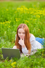 Smiling girl with laptop on grass