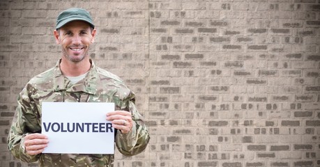 Soldier volunteer against brown brick wall