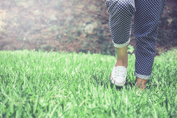 Legs of women walking on a green meadow.