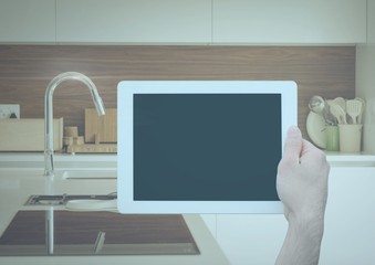 Hand holding tablet in kitchen