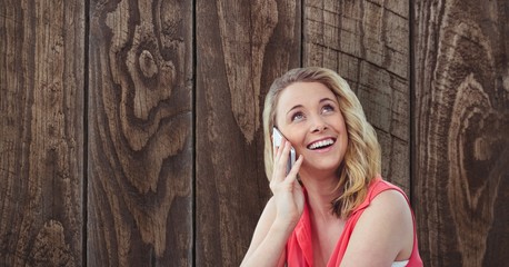Fototapeta premium Happy woman using smart phone against wooden 