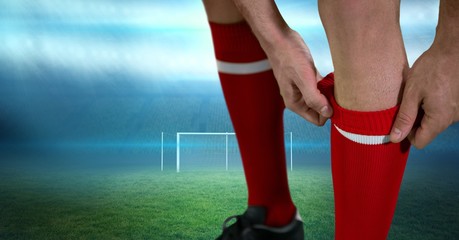 Close-up of soccer player adjusting sock on field