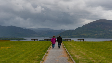 Fototapeta premium Couple walking on a path towards a viewing point of the lakes and mountains of Killarney national park