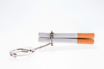 Addition concept with cigarettes and handcuffs on white background
