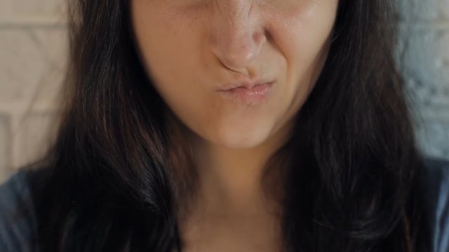 Beautiful woman is angry and upset. Showing anger with her lips. Close up. Brown hair. Slow motion