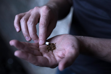 Male drug addicted holding marijuana cigarette in the dark place