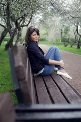 Smiling girl sits on a park bench 
