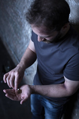 Homeless man holding marijuana cigarette in the dark corner