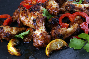 barbecue chicken wings close up on stone tray with pepper and lime
