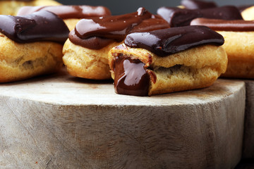 Traditional French dessert. Eclair with chocolate icing. Wooden background