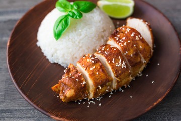 On a clay plate lies a teriyaki chicken with rice and fresh basil, lime, sesame, Japanese style...