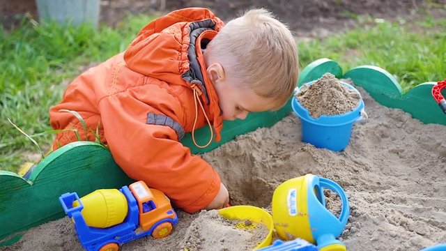 the child plays with the toys in the sandbox. close-up