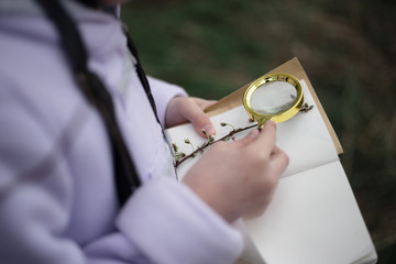 Detail of girl's hands holding a notebook, attaching speciments to her herbarium. Shot on location, natural light, lifestyle image.