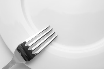Fork on a empty plate, cutlery and copy space, on a white background