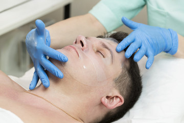 Obraz na płótnie Canvas Man in the mask cosmetic procedure in spa salon 
