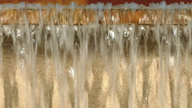 Detail of continuous movement of water falling into a fountain, creating a water curtain.