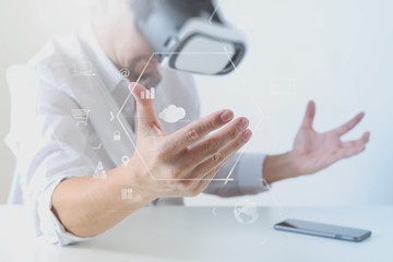 Fototapeta premium businessman wearing virtual reality goggles in modern office with mobile phone using with VR headset with screen icon diagram