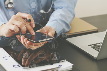 smart medical doctor working with smart phone and stethoscope and laptop and digital tablet computer on dark wooden desk