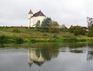 Fototapeta na wymiar Old church on a hill, reflection in a river 