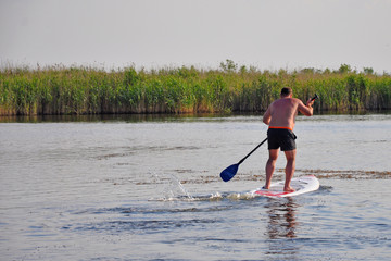 Male of European appearance is on the Board and rowing with a paddle