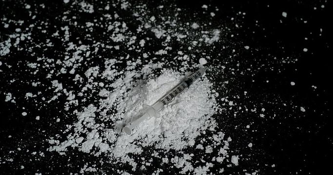 Syringe Falling on Drug Powder against Black Background, Slow Motion 4K