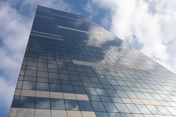 Fototapeta na wymiar Modern office building on sky background with clouds reflection