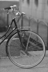 Black bicycle with white wheels on a blurred city background.