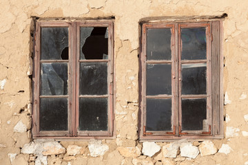 Old windows with broken panes on the wall of a old building